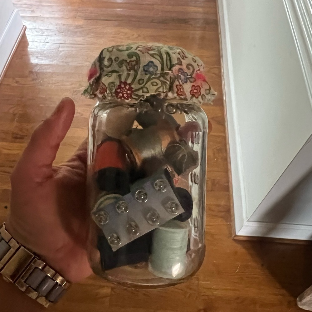 Glass jar with fabric top, filled with random sewing 🧵 items, some are antique.